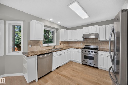 Kitchen featuring white cabinetry, stainless steel appliances, granite countertops, and wood-finish flooring - 3640 31 Street Nw, Edmonton, AB - Indoor Photo Showing Kitchen With Stainless Steel Kitchen