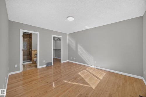 Hardwood flooring, light gray wall finishes, recessed lighting fixture, walk-in closet, and a bathroom with a glass-enclosed shower - 3640 31 Street Nw, Edmonton, AB - Indoor Photo Showing Other Room