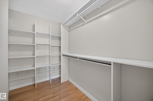 Walk-In Closet.  Custom built-in shelving, integrated hanging rods, and wood-finish flooring. - 3640 31 Street Nw, Edmonton, AB - Indoor With Storage