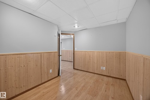 Bedroom 6.  Wood-finish flooring, light grey painted walls, natural wood wainscoting, and a drop ceiling with recessed lighting - 3640 31 Street Nw, Edmonton, AB - Indoor Photo Showing Other Room