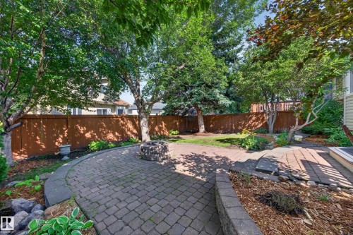 Paver patio with a built-in stone fire pit, wood fencing, and mature trees - 3640 31 Street Nw, Edmonton, AB - Outdoor