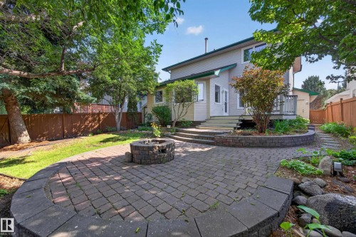 Expansive backyard featuring a paver patio with a built-in fire pit, multiple mature trees, and a wooden fence - 3640 31 Street Nw, Edmonton, AB - Outdoor