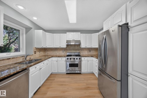 White cabinetry with paneled doors, stainless steel appliances, wood-finish flooring, recessed lighting, and a window - 3640 31 Street Nw, Edmonton, AB - Indoor Photo Showing Kitchen With Stainless Steel Kitchen With Double Sink