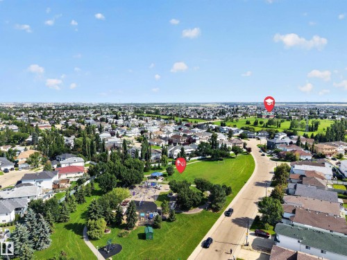 Aerial view of a residential area featuring numerous homes, expansive green spaces, a public park with play equipment, and mature trees - 3640 31 Street Nw, Edmonton, AB - Outdoor With View