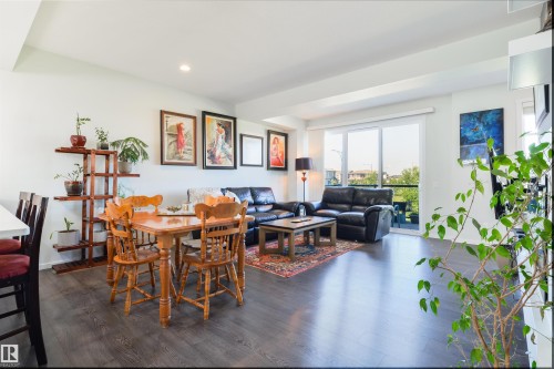 Open-concept living space with dark wood-finish flooring, recessed lighting, and a sliding glass door to an exterior balcony - 8265 Chappelle Way Sw, Edmonton, AB - Indoor