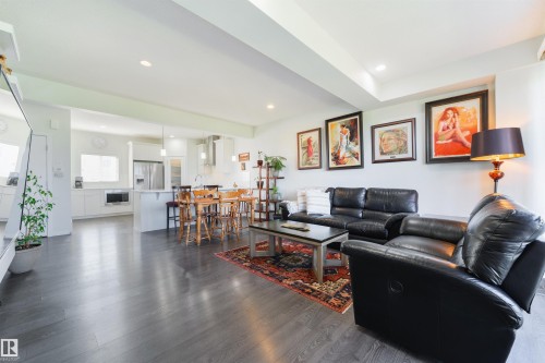 Open-concept living space featuring wood-finish flooring, recessed lighting, and a kitchen with an island and stainless steel appliances - 8265 Chappelle Way Sw, Edmonton, AB - Indoor Photo Showing Living Room