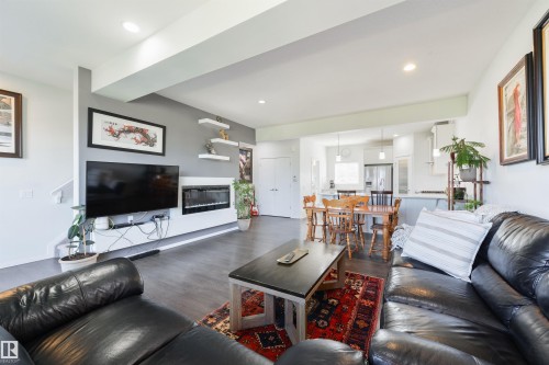Open-concept living space featuring wood-finish flooring, recessed lighting, and a linear electric fireplace - 8265 Chappelle Way Sw, Edmonton, AB - Indoor Photo Showing Living Room