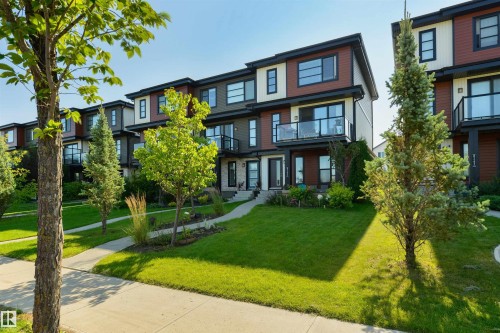 Modern townhome exterior with contrasting siding, black-framed windows, and glass-paneled balconies - 8265 Chappelle Way Sw, Edmonton, AB - Outdoor With Facade