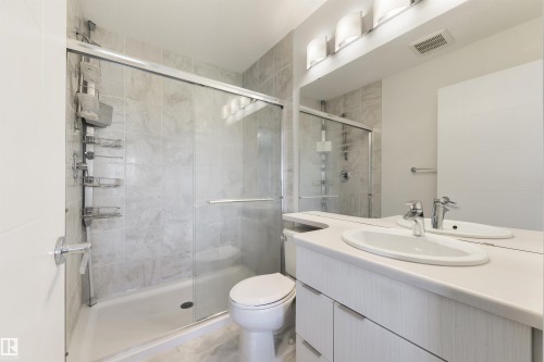 Glass-enclosed shower with tile surround, single vanity with integrated sink, chrome fixtures, and built-in mirror - 8265 Chappelle Way Sw, Edmonton, AB - Indoor Photo Showing Bathroom