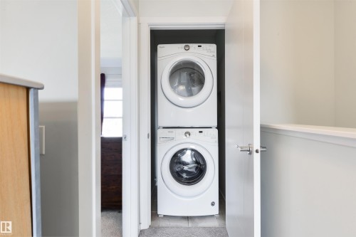 In-unit stacked washer and dryer appliances - 8265 Chappelle Way Sw, Edmonton, AB - Indoor Photo Showing Laundry Room
