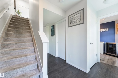 Carpeted staircase with white risers, wood-finish flooring, and white interior doors - 8265 Chappelle Way Sw, Edmonton, AB - Indoor Photo Showing Other Room