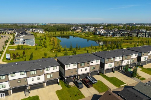 Modern townhome exteriors with dark roofs, contrasting siding, and attached garages - 8265 Chappelle Way Sw, Edmonton, AB - Outdoor With Body Of Water With View