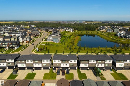 Modern townhomes featuring a contemporary exterior, attached garages, and a paved driveway - 8265 Chappelle Way Sw, Edmonton, AB - Outdoor With Body Of Water With View