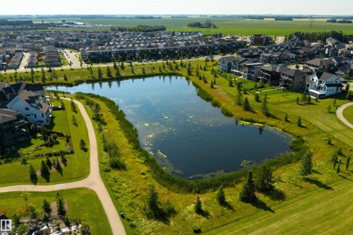 Landscaped pond with a pedestrian pathway, surrounded by manicured lawns and mature trees - 8265 Chappelle Way Sw, Edmonton, AB - Outdoor With Body Of Water With View
