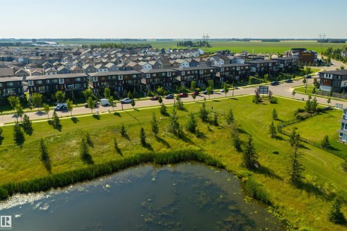 Community with a central pond, surrounding green spaces, and modern townhomes - 8265 Chappelle Way Sw, Edmonton, AB - Outdoor With Body Of Water With View