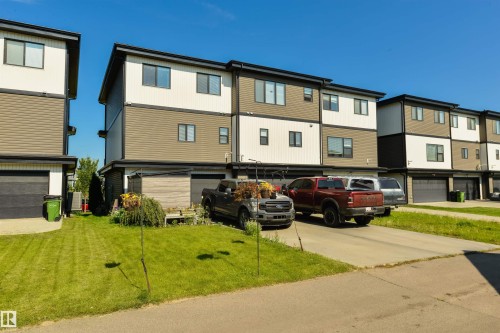 Modern multi-level exterior with a flat roofline, featuring two-tone siding, dark-framed windows, and an attached garage with a black door - 8265 Chappelle Way Sw, Edmonton, AB - Outdoor