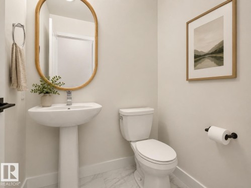 Pedestal sink with chrome faucet, oval mirror, and white toilet - #53 16231 19 Av Sw, Edmonton, AB - Indoor Photo Showing Bathroom