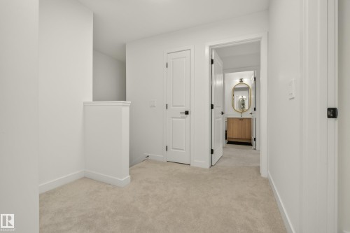 Light-colored carpeting, white interior doors with black hardware, and a half-wall partition - #53 16231 19 Av Sw, Edmonton, AB - Indoor Photo Showing Other Room