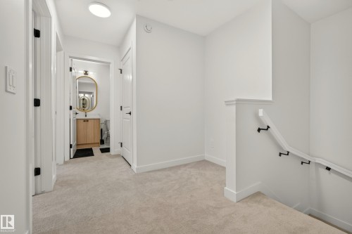 Hallway with neutral carpeting, white walls, and black hardware on doors - #53 16231 19 Av Sw, Edmonton, AB - Indoor Photo Showing Other Room