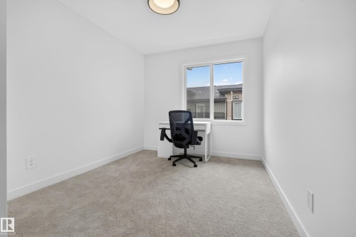 Light-toned carpet flooring, white walls, a large window with white trim, and a flush-mount ceiling light - #53 16231 19 Av Sw, Edmonton, AB - Indoor