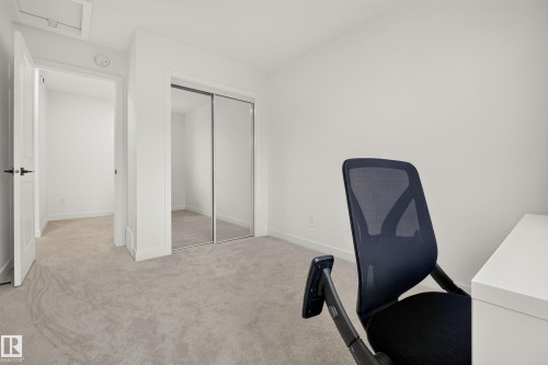 Neutral-toned carpeting, white painted walls, and a closet with mirrored sliding doors - #53 16231 19 Av Sw, Edmonton, AB - Indoor Photo Showing Other Room
