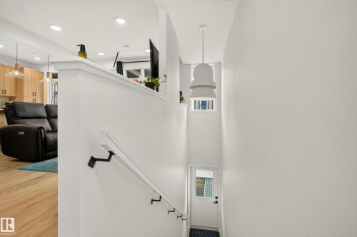 Open-concept living space with wood-finish flooring, recessed lighting, and a white half-wall - #53 16231 19 Av Sw, Edmonton, AB - Indoor Photo Showing Other Room