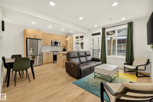 Open-concept living space with wood-finish flooring, recessed lighting, and ample natural light from large windows - #53 16231 19 Av Sw, Edmonton, AB - Indoor