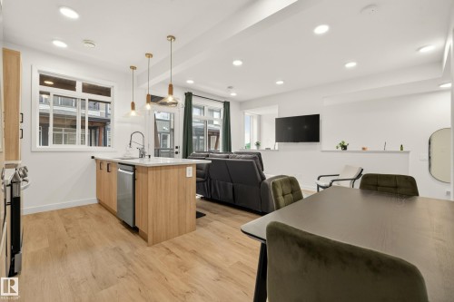 Open-concept living space featuring wood-finish flooring, recessed lighting, and a kitchen island with a built-in dishwasher - #53 16231 19 Av Sw, Edmonton, AB - Indoor