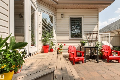 Patio area featuring light-colored siding, a wood-finish deck, and a brick paver section - 9135 100B Avenue Nw, Edmonton, AB - Outdoor With Deck Patio Veranda With Exterior