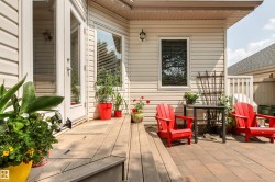 Patio area featuring light-colored siding, a wood-finish deck, and a brick paver section - 
