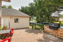 Expansive paver patio with a stacked stone outdoor kitchen island, providing an ideal setting for outdoor cooking - 