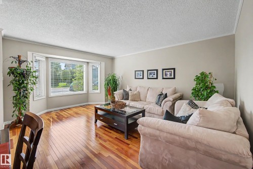 Hardwood flooring, bay window, white window blinds, light-toned wall paint, and crown molding - 193 Kiniski Crescent Nw, Edmonton, AB - Indoor Photo Showing Living Room