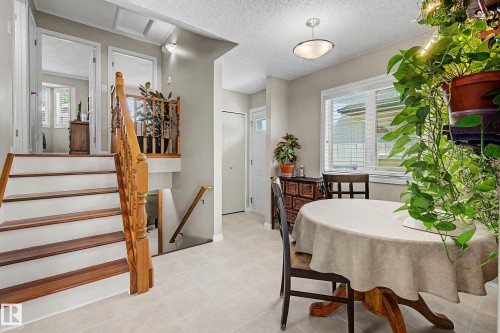 Staircase with wood-finish treads and railing, light-toned tile flooring, and a ceiling-mounted light fixture - 193 Kiniski Crescent Nw, Edmonton, AB - Indoor