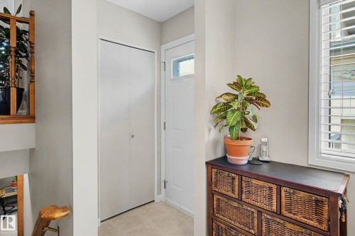 Bright entryway featuring neutral wall finishes, a white six-panel closet door, wood-finish cabinetry with woven rattan front panels, and abundant natural light from multiple windows - 193 Kiniski Crescent Nw, Edmonton, AB - Indoor Photo Showing Other Room