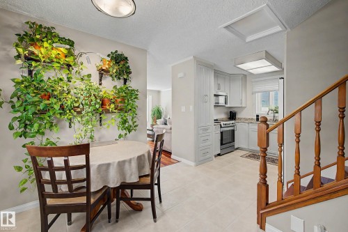 Light-toned wall paint and trim, wood stair railing, tiled flooring, built-in cabinetry, and stainless steel appliances - 193 Kiniski Crescent Nw, Edmonton, AB - Indoor Photo Showing Dining Room