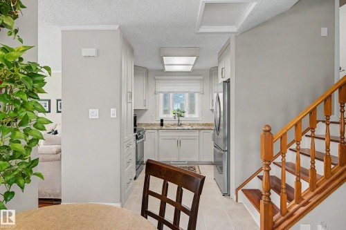 Galley kitchen with light-colored cabinetry, stone-finish countertops, stainless steel appliances, and a window with blinds - 193 Kiniski Crescent Nw, Edmonton, AB - Indoor