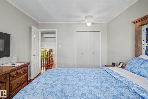 Ceiling fan, wood-finish flooring, white bi-fold closet doors, white interior doors with glass panels, wall-mounted air conditioning unit - 193 Kiniski Crescent Nw, Edmonton, AB - Indoor Photo Showing Bedroom