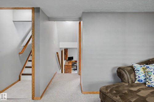 Stairwell with wood-finish handrails and trim, white risers, and light-colored floor tiles - 193 Kiniski Crescent Nw, Edmonton, AB - Indoor Photo Showing Other Room