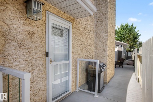 Exterior entry featuring a textured stucco finish, a white storm door, and an exterior wall lantern - 193 Kiniski Crescent Nw, Edmonton, AB - Outdoor With Exterior
