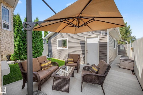 Backyard patio featuring light-toned decking, an adjacent lawn area, and a detached structure with horizontal siding - 193 Kiniski Crescent Nw, Edmonton, AB - Outdoor With Deck Patio Veranda With Exterior