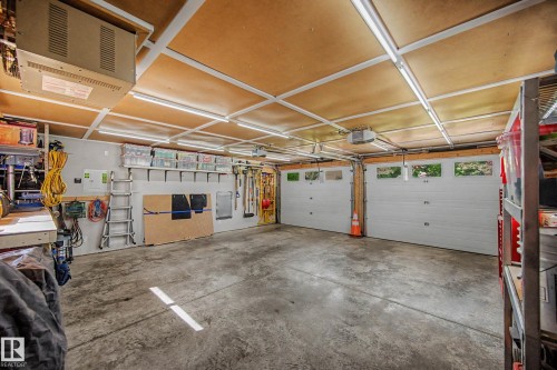 Concrete flooring, two overhead garage doors with window panels, multiple fluorescent light fixtures, and wall-mounted shelving - 193 Kiniski Crescent Nw, Edmonton, AB - Indoor Photo Showing Garage
