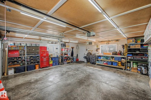 Spacious garage with concrete flooring, multiple overhead light fixtures, and a workbench with built-in shelving - 193 Kiniski Crescent Nw, Edmonton, AB - Indoor Photo Showing Garage
