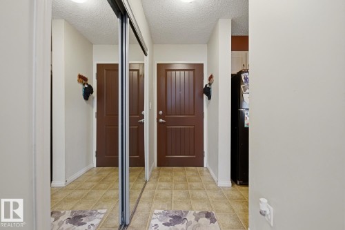 Mirrored sliding closet doors, ceiling-mounted light fixture, and tile flooring - #106 13907 136 St Nw, Edmonton, AB - Indoor Photo Showing Other Room