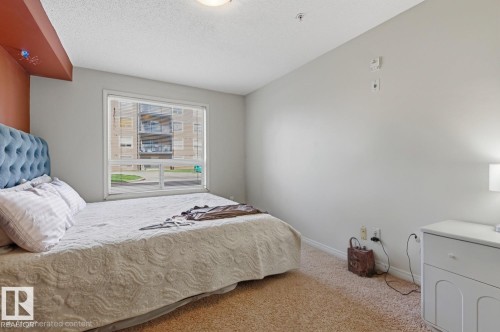 Hardwood-finish flooring, white walls, and a large window with white trim - #106 13907 136 St Nw, Edmonton, AB - Indoor Photo Showing Bedroom