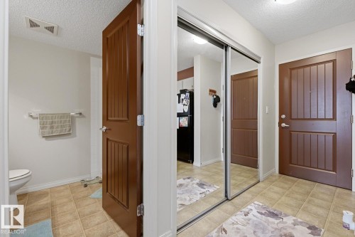 Tile flooring in a neutral tone, full-height mirrored closet doors, and wood-paneled interior doors - #106 13907 136 St Nw, Edmonton, AB - Indoor Photo Showing Bathroom