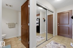 Tile flooring in a neutral tone, full-height mirrored closet doors, and wood-paneled interior doors - 