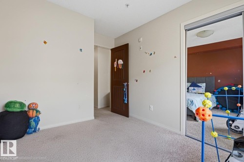 Mirrored closet doors, flush-mount ceiling light, paneled interior door, and neutral-toned carpeting - #106 13907 136 St Nw, Edmonton, AB - Indoor Photo Showing Other Room