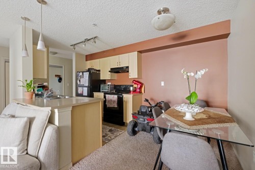 Kitchen featuring light wood-finish cabinetry, black appliances, a double basin sink, and pendant lighting - #106 13907 136 St Nw, Edmonton, AB - Indoor
