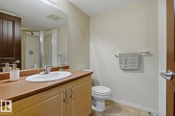 Bathroom featuring an integrated sink, light-toned cabinetry, a spacious vanity, a glass-enclosed shower, and tile flooring - 