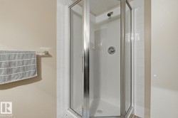 Corner shower enclosure with clear glass panels, chrome hardware, and white tile surround - 